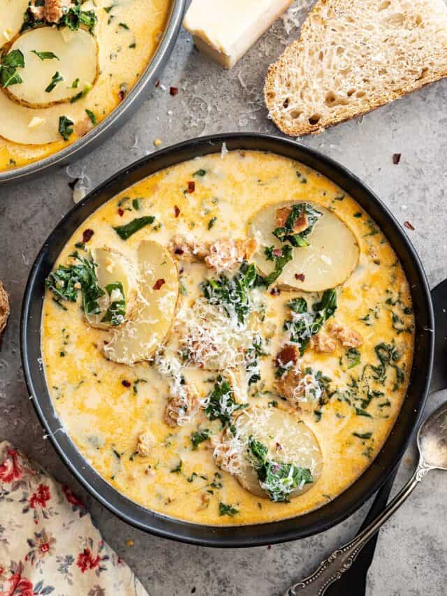 Overhead view of a bowl of soup. A chunk of parmesan off to the side along with slices of bread.