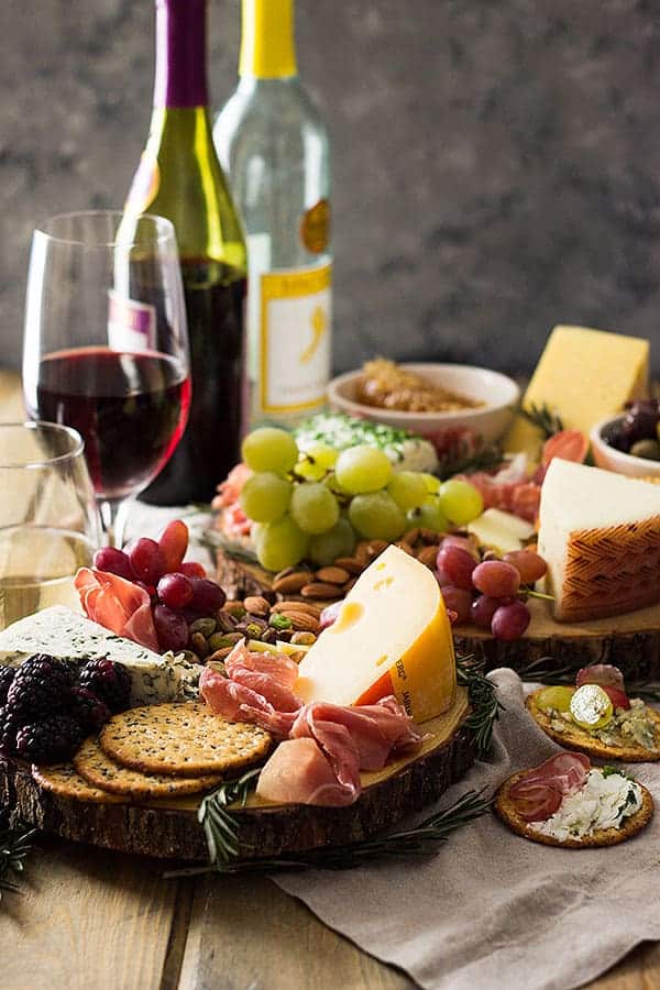 charcuterie board cheese with meat, nuts, crackers, fruit, and a few glasses of wine to the side