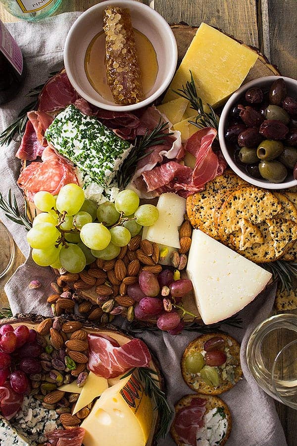 overhead closeup: cheese for charcuterie board with meat, nuts, fruit, and crackers