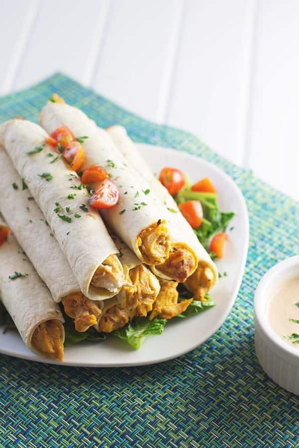 overhead: a plate of chicken taquitos with dipping sauce to the side