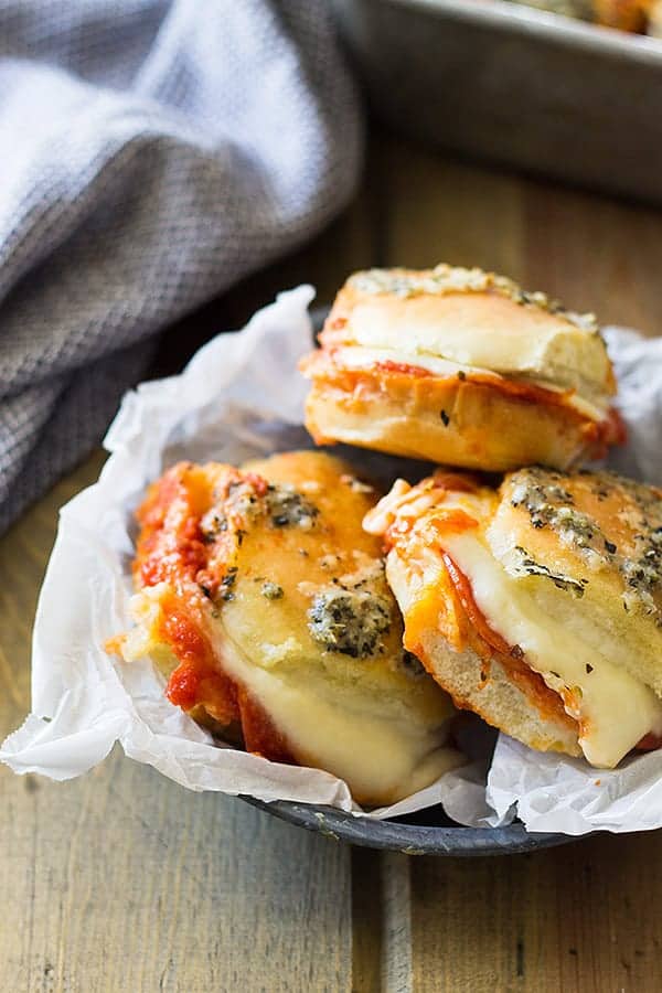3 hawaiian roll pizza sliders in a basket with parchment paper