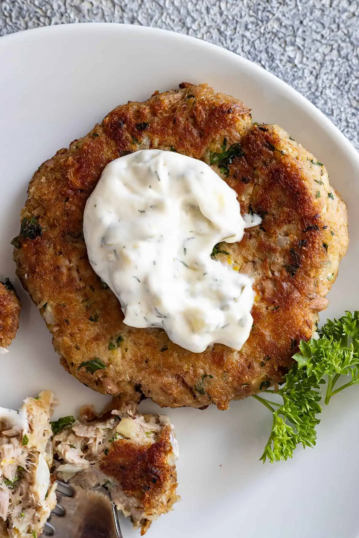 Overhead view of tartar sauce on a tuna patty. 