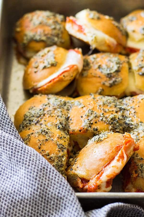 closeup: a large pan of pizza sliders topped with cheese and herbs