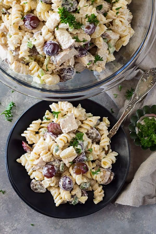 overhead: grilled chicken pasta salad on a black plate and in glass mixing bowl