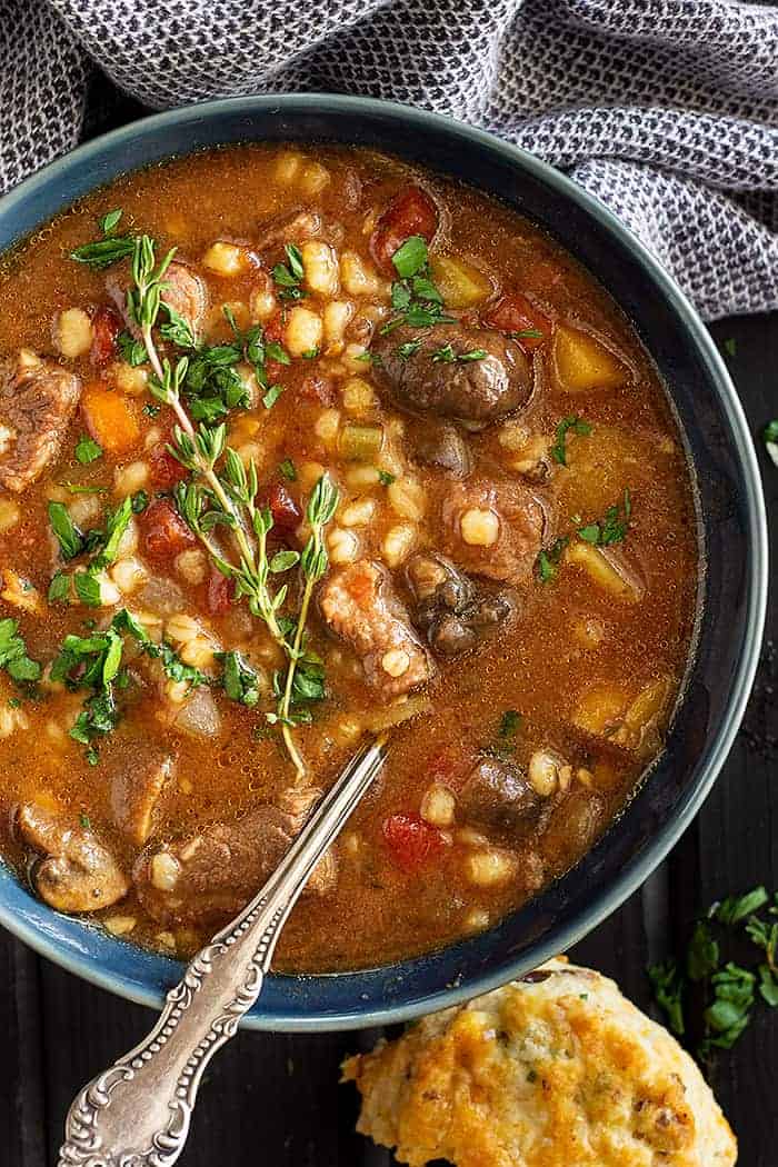 overhead: beef barley soup instant pot in a blue bowl with a spoon