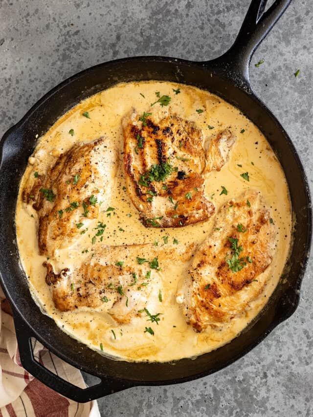 Overhead view of creamy garlic chicken in a cast iron pan.