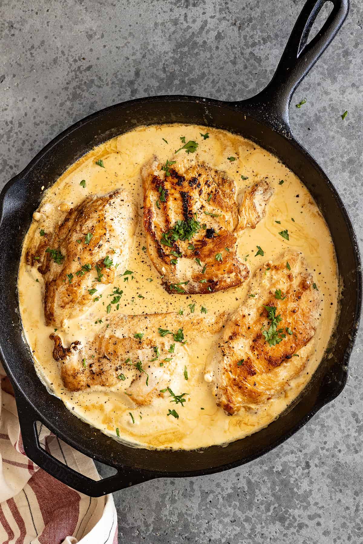 Overhead view of creamy garlic chicken in a cast iron pan. 