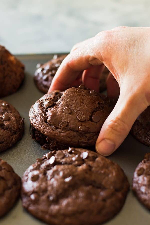 cloeup: a hand lifting a strawberry chocolate chip muffin out of a muffin tin