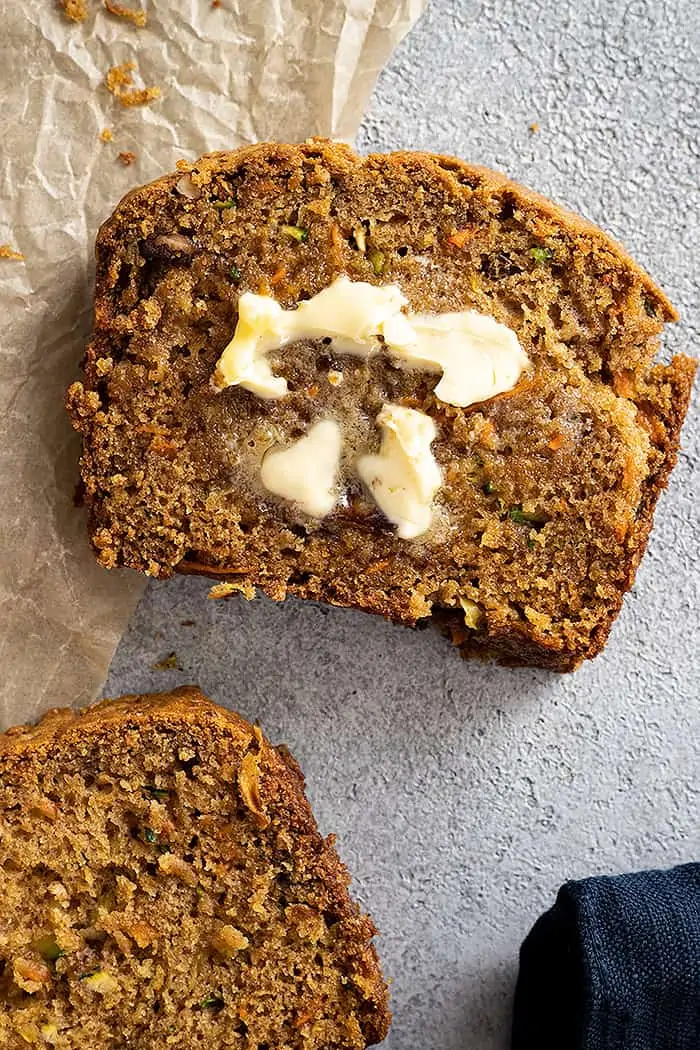 overhead: a slice of zucchini and carrot bread with a pat of butter melting