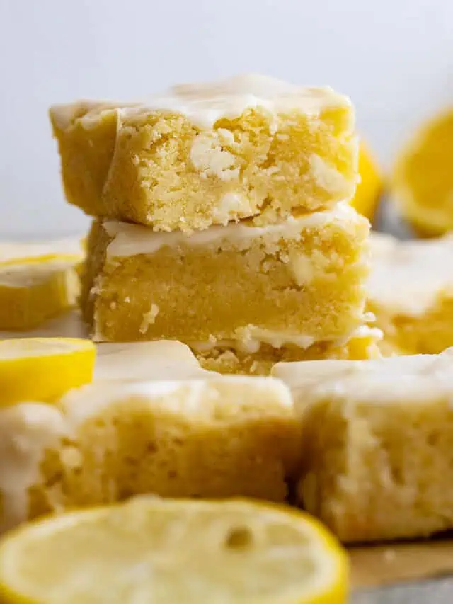 Stack of lemon brownies with sliced lemons around.