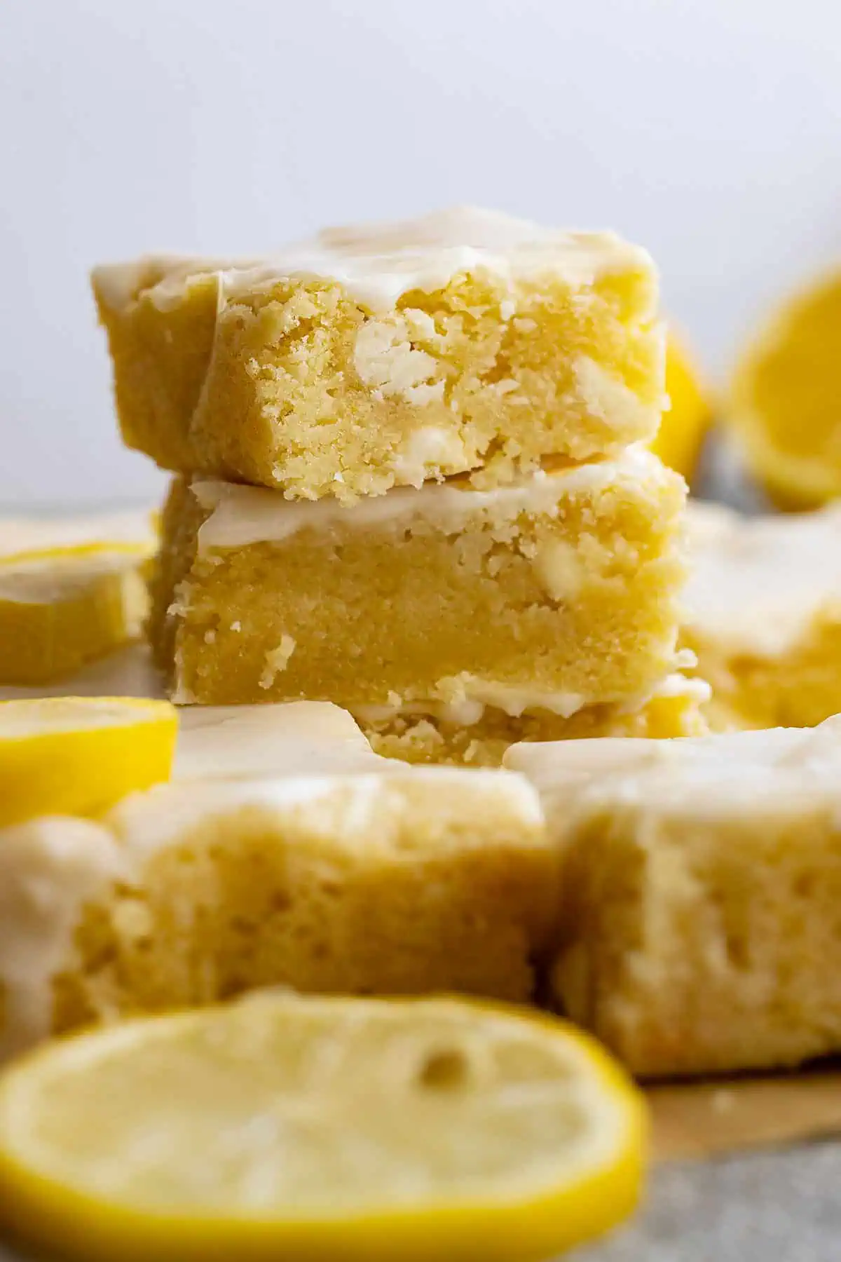 Stack of lemon brownies with sliced lemons around.