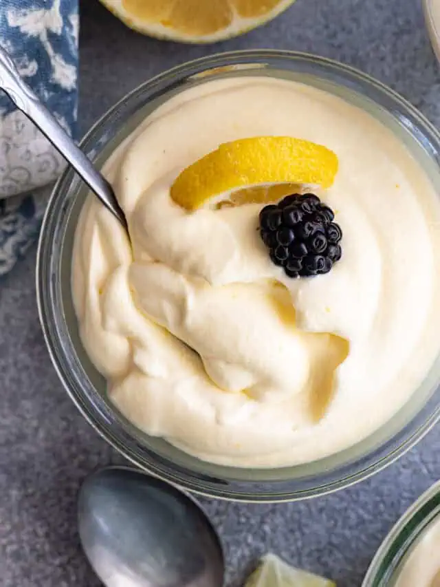 Overhead view of lemon mousse garnished a blackberry and lemon slice. Spoon in the mousse.