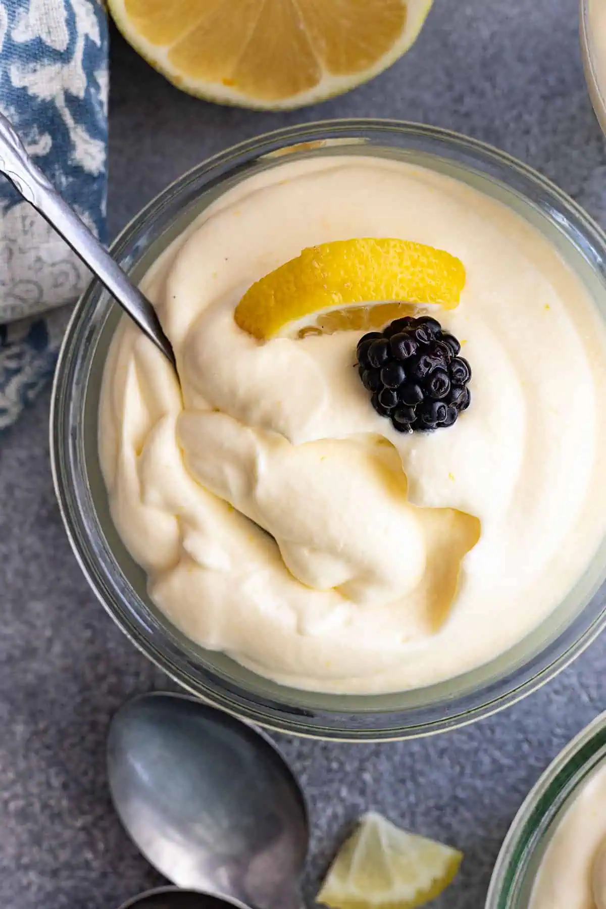 Overhead view of lemon mousse garnished a blackberry and lemon slice. Spoon in the mousse. 