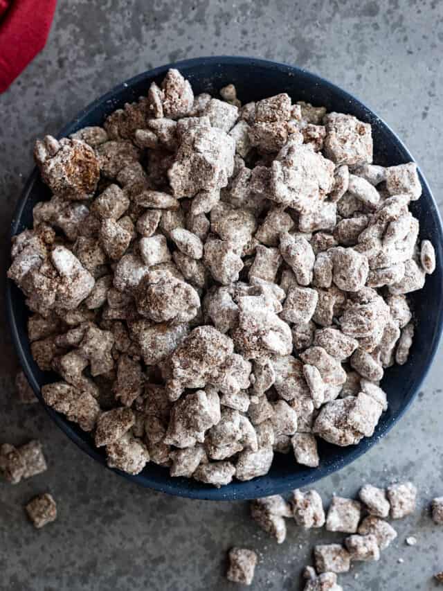 Overhead picture of muddy buddies in a large bowl. Some spilled out of the bowl.