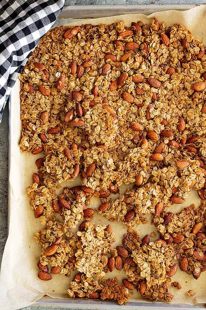 overhead: honey almond granola on a parchment lined baking sheet after baking