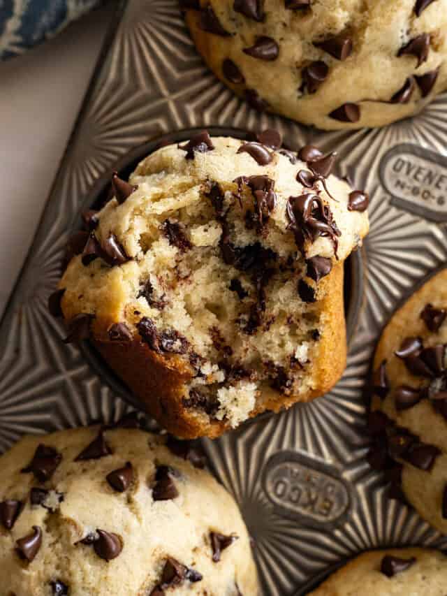 Close up of muffin with bite taken out showing all the chocolate chips inside the muffin.