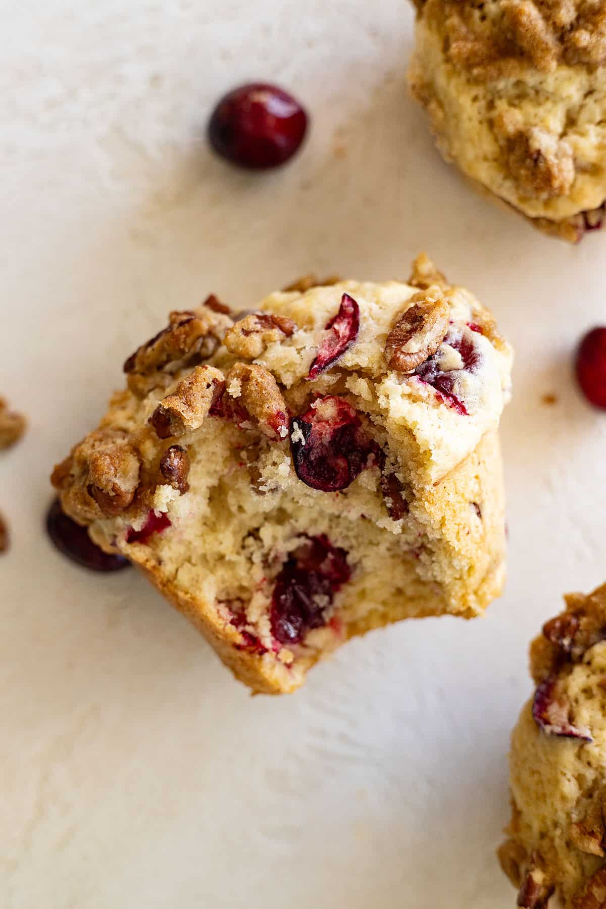 Close up of cranberry pecan muffin with a bite taken out showing the inside. 