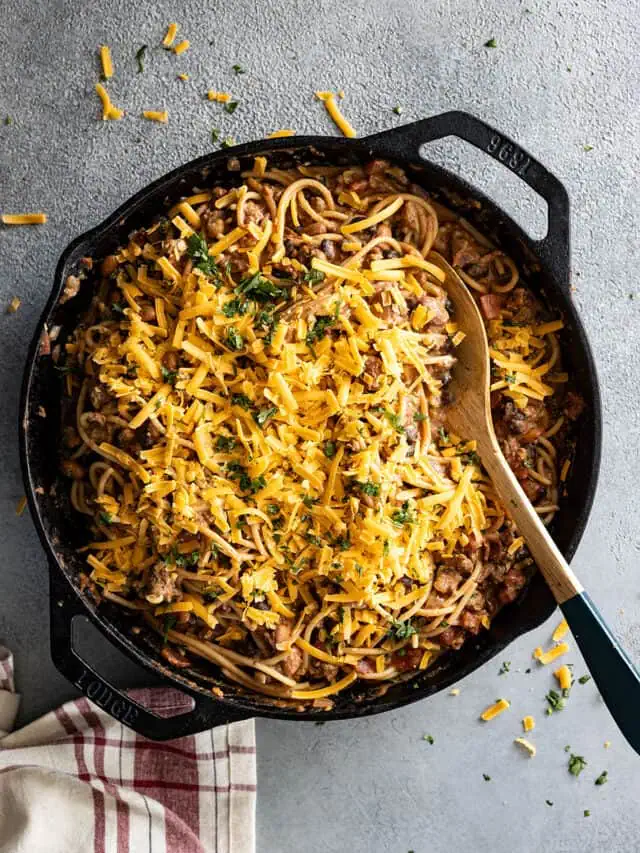 Overhead view of cowboy spaghetti in a cast iron skillet with cheese sprinkled on top.