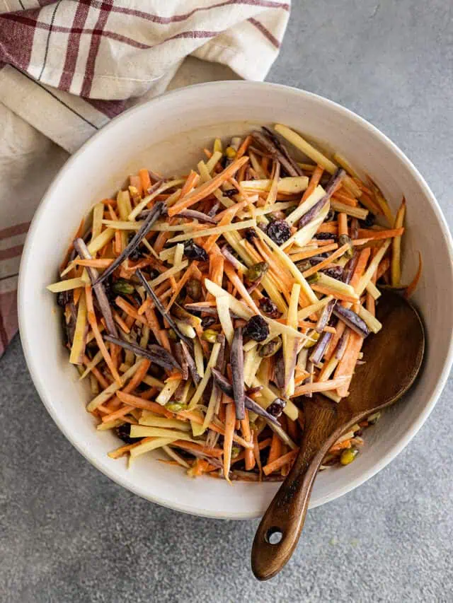 Overhead picture of carrot salad in a large serving bowl with spoon off to the side.