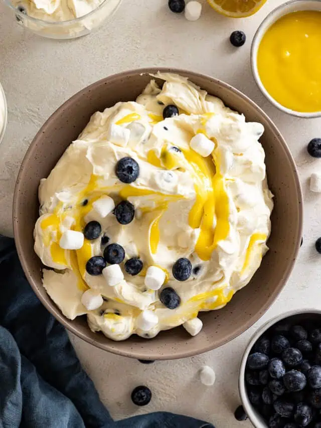 Overhead view of lemon blueberry fluff in a large bowl. Garnished with blueberries, marshmallows, and lemon curd.