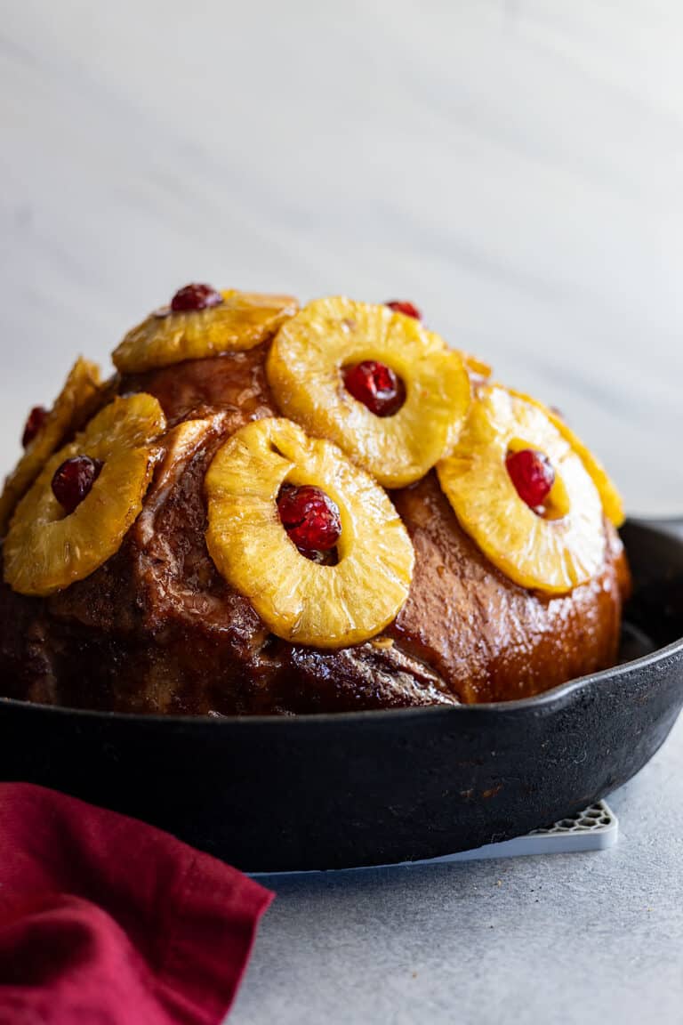 Pineapple ham in a cast iron skillet with red napkin off to the side.