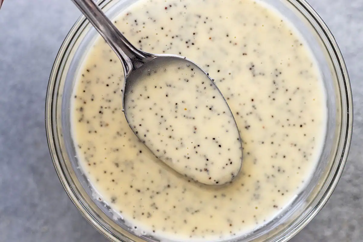 Overhead view of a spoon lifting up some dressing from a bowl.