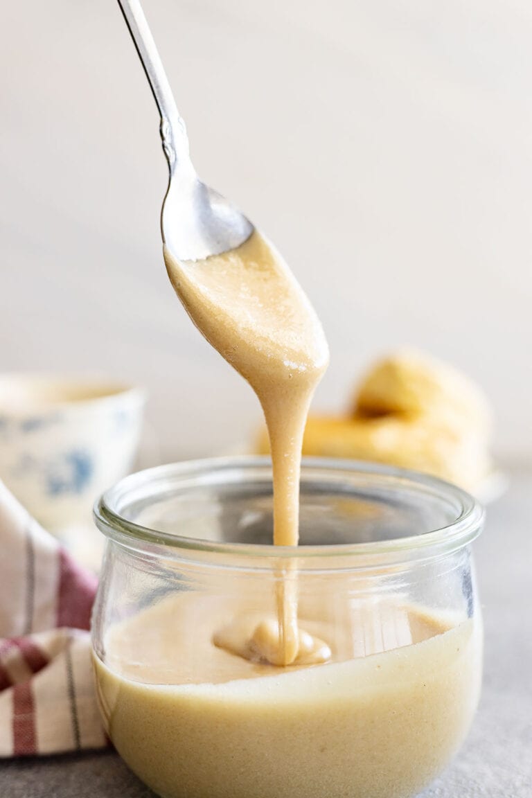 Spoon pulling up whipped honey from a jar.