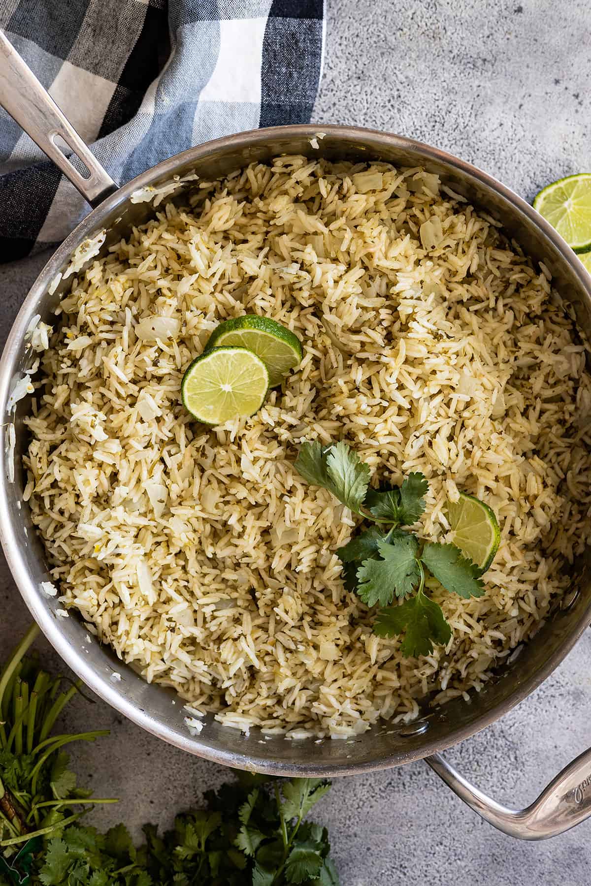 Overhead view of Mexican Green Rice in a skillet garnished with limes and cilantro.