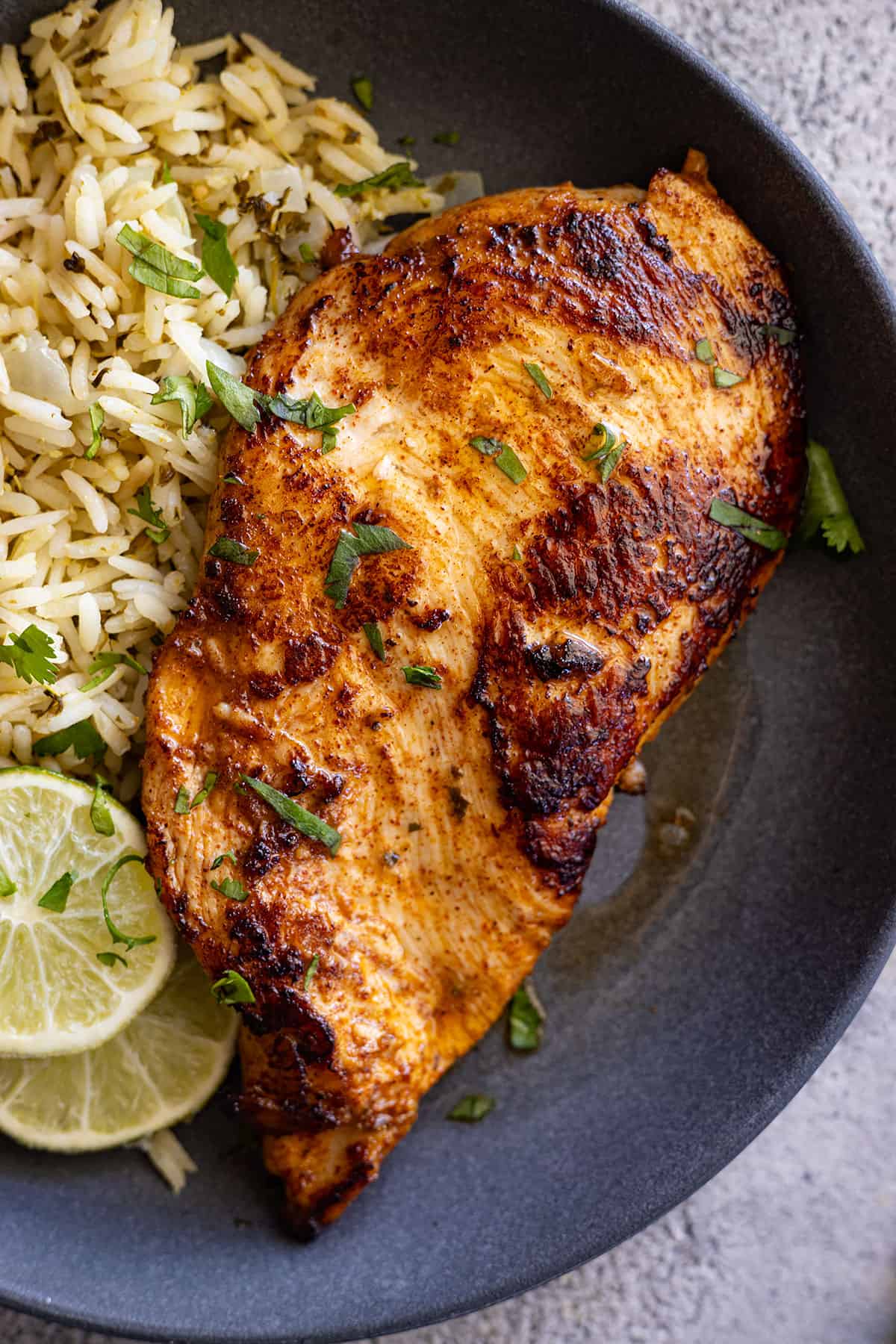 Overhead view of chicken on a blue plate with rice off to the side.