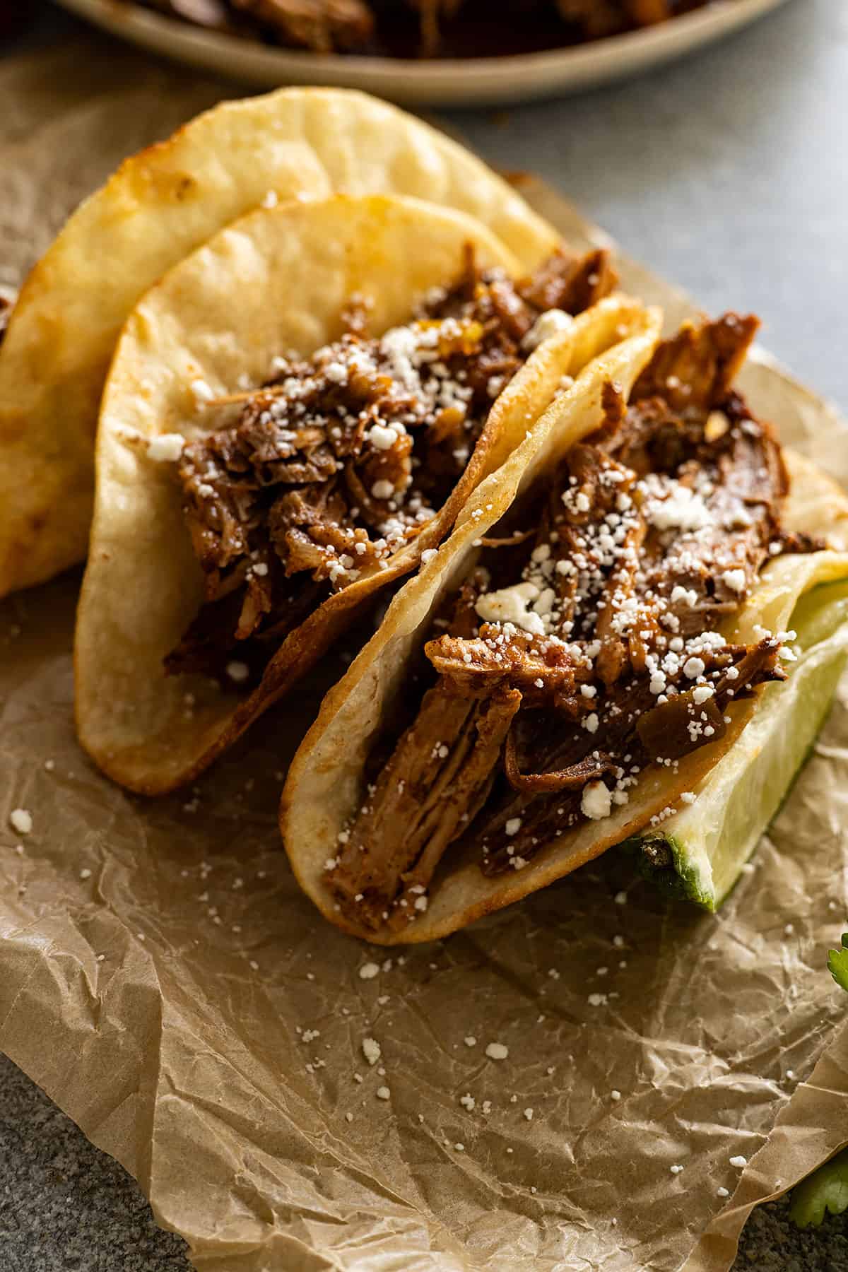 Close up of pork tacos sprinkled with cheese. 