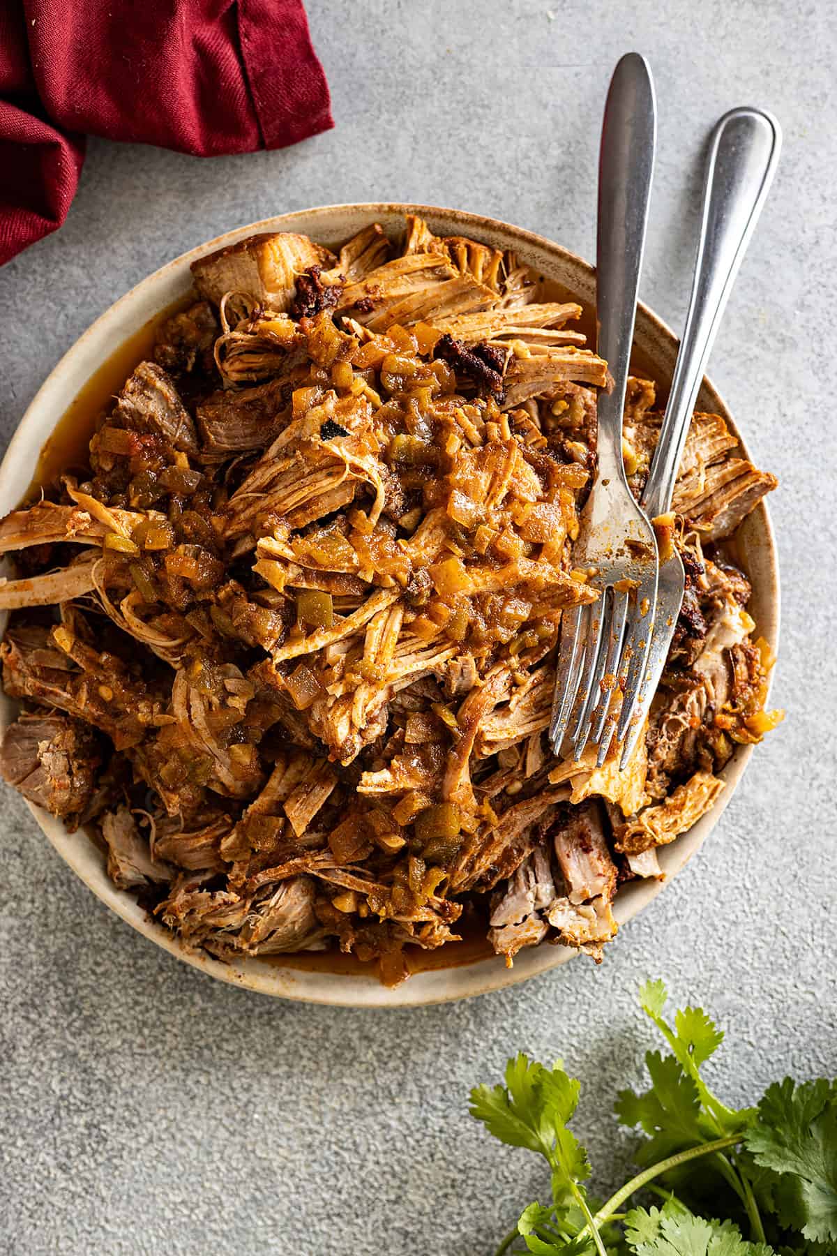 Overhead view of pork taco meat on a plate with forks off to the side.