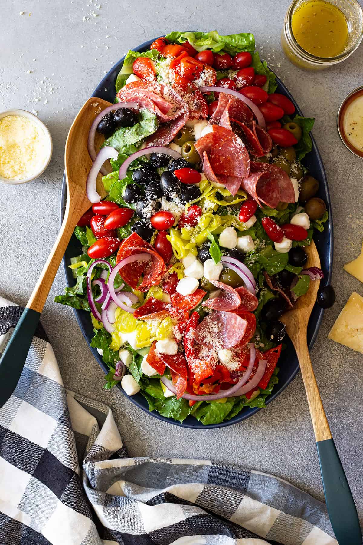 Big platter of antipasto salad with salad spoons in the side.