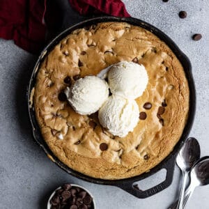 Overhead view of chocolate chip skillet cookie with vanilla ice cream on top ready to eat.