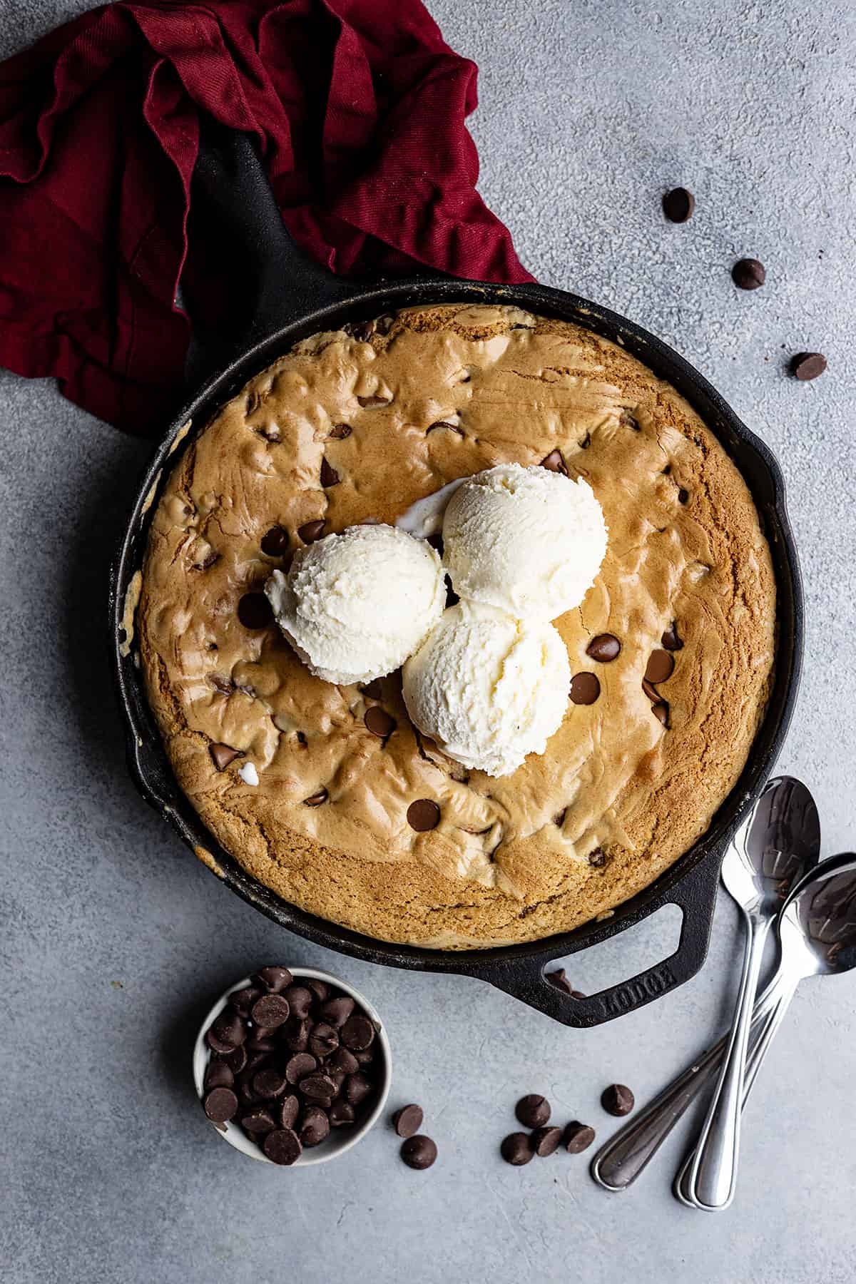 Overhead view of chocolate chip skillet cookie with vanilla ice cream on top ready to eat. 