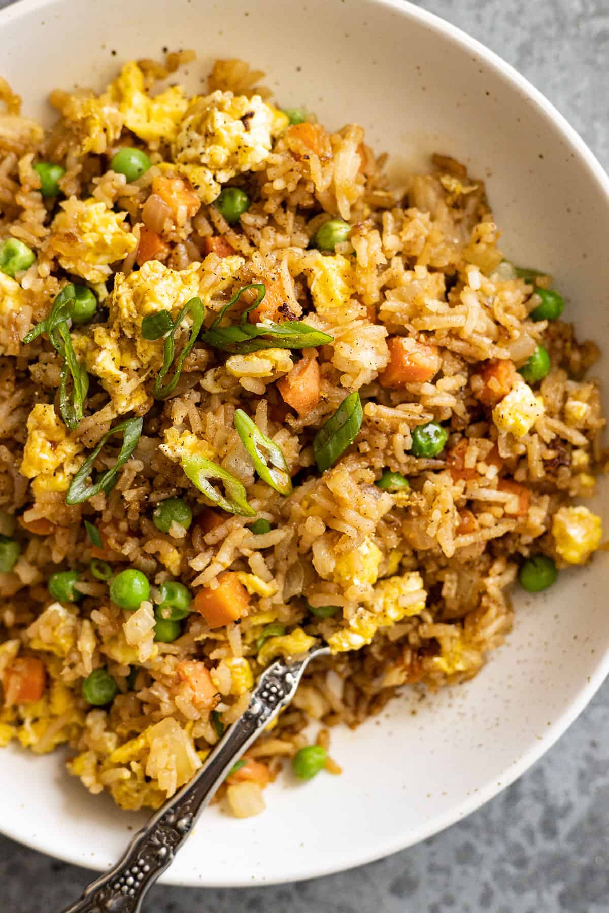 Overhead view of rice in a bowl with fork. Garnished with green onion. 