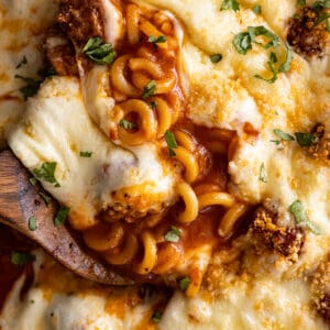 Close up of cheesy spaghettios with meatballs with a spoon in it.