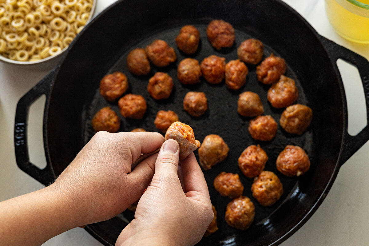 Picture showing how to squeeze out a small portion of meat from the casing right into the pan to make the meatballs. 