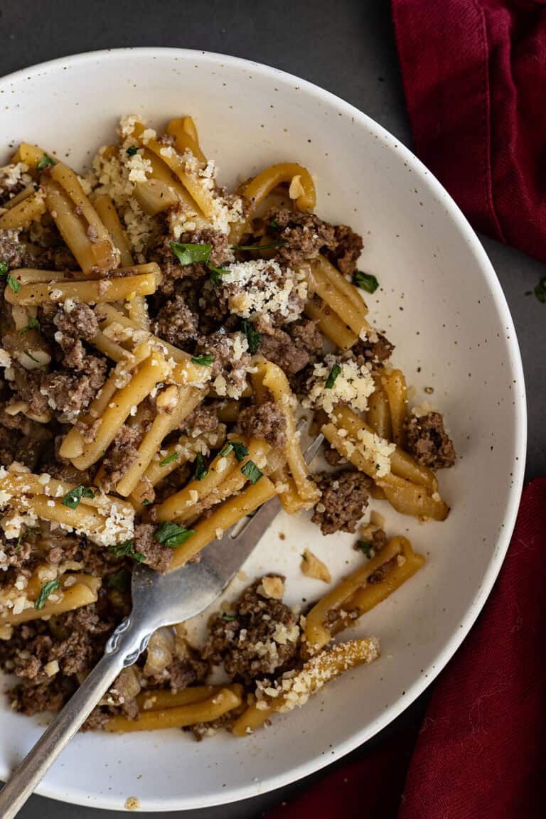 Close up of pasta in a white dish with a fork in it.