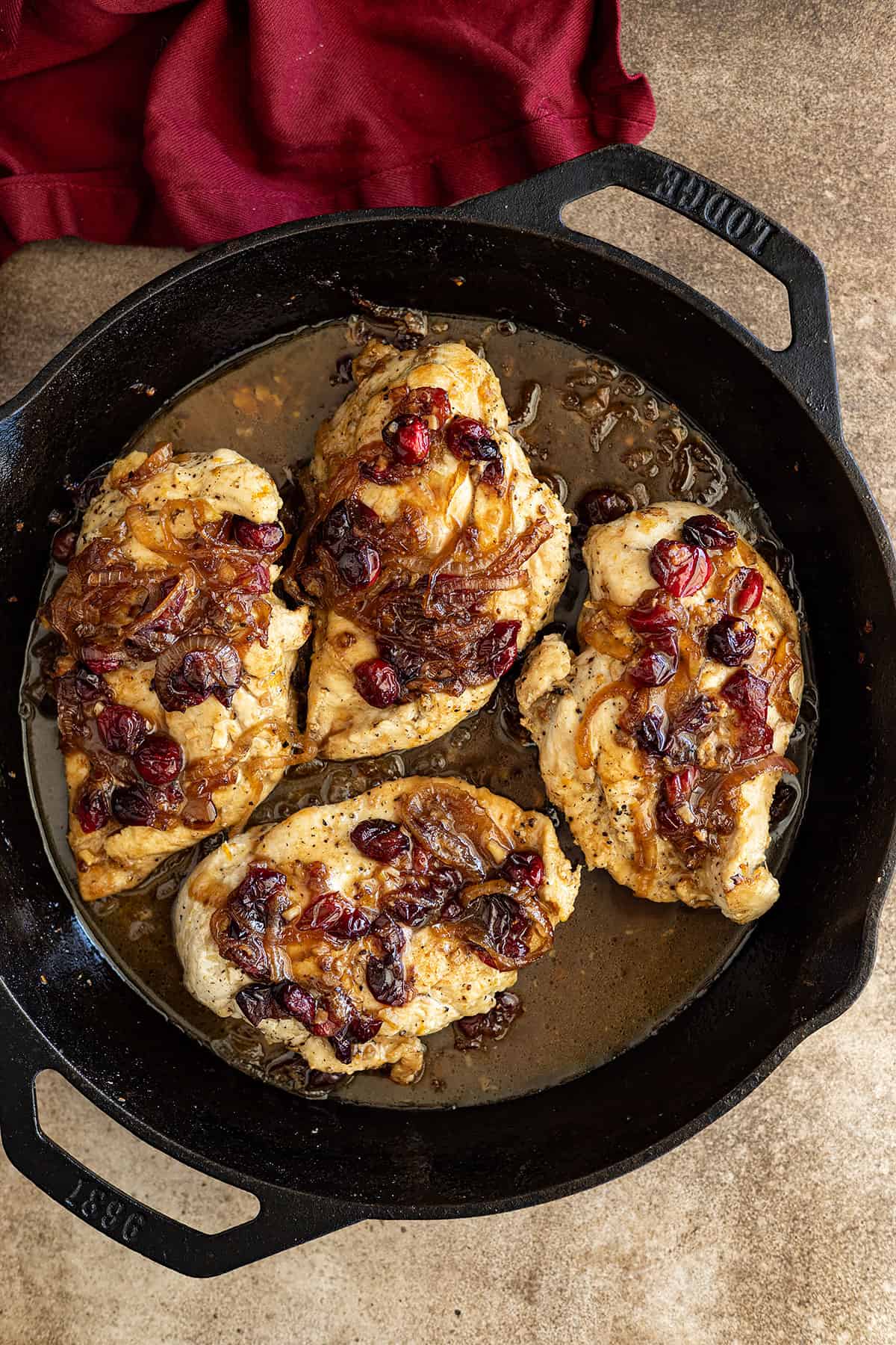 Overhead view of baked cranberry chicken in a cast iron skillet fresh from the oven.