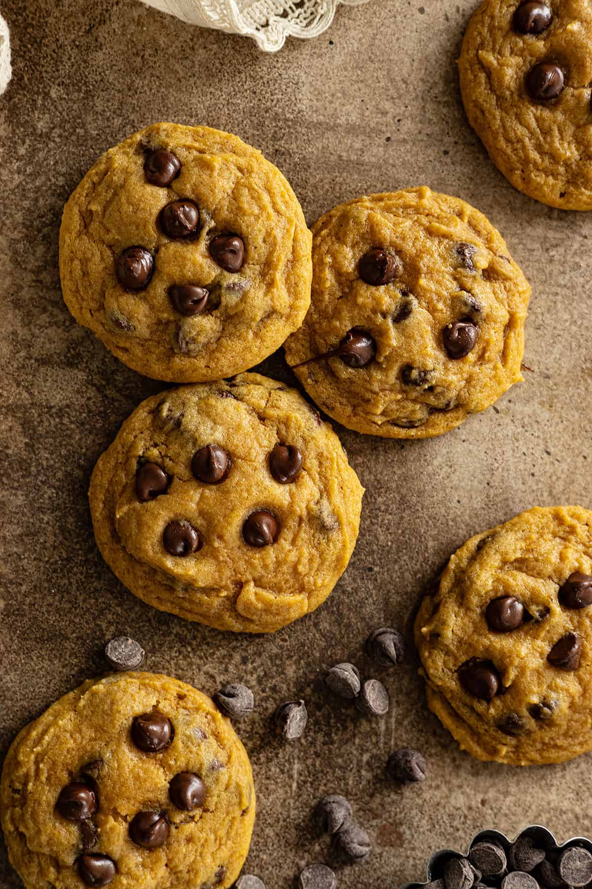 Close up of cookies alongside scattered chocolate chips. 