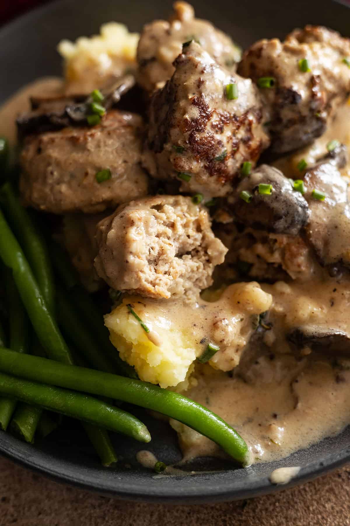 close up of meatball with bite taken out. 