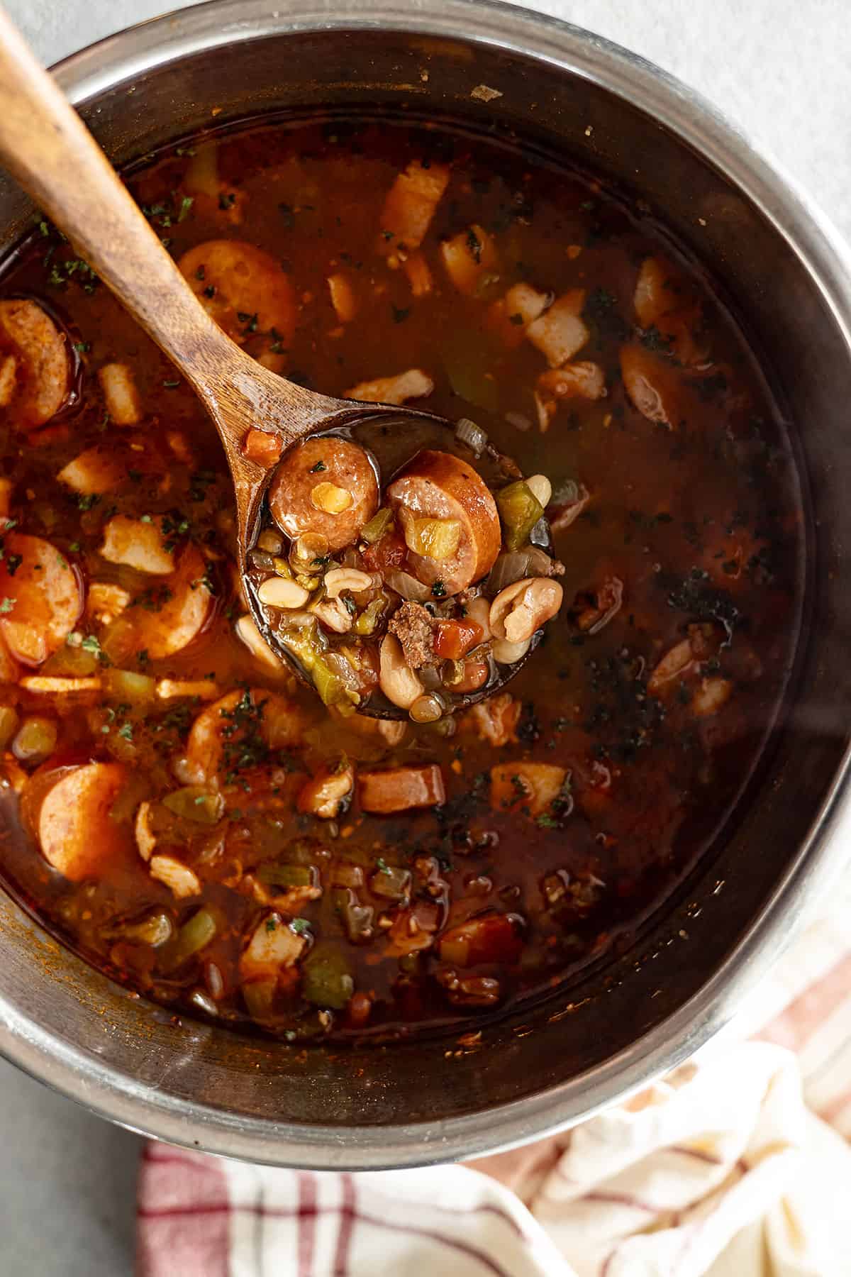 overhead view of cowboy 15 bean soup done cooking. ladle bringing up soup to serve.