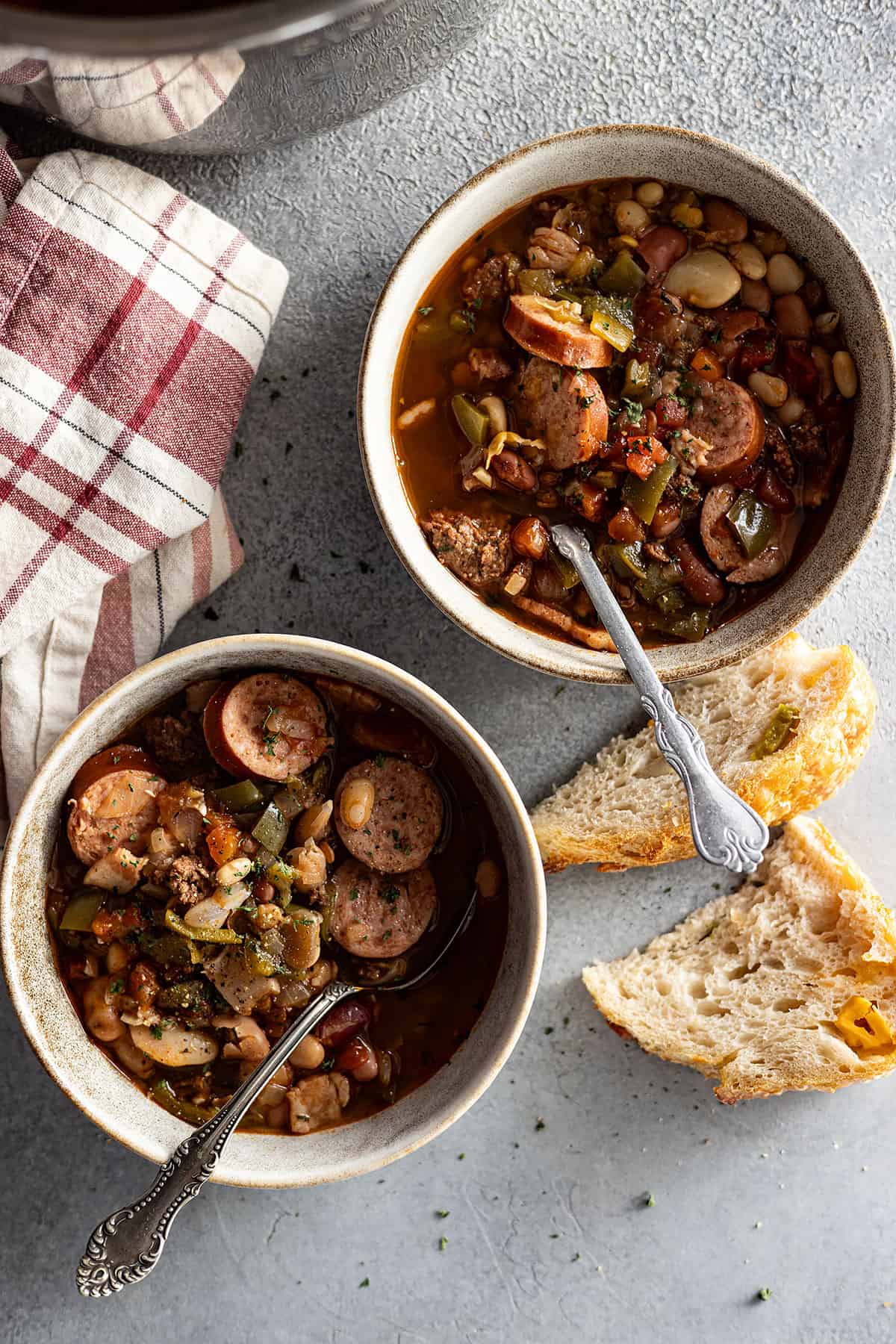 overhead view of two bowls of cowboy 15 bean soup. crusty bread to the side.