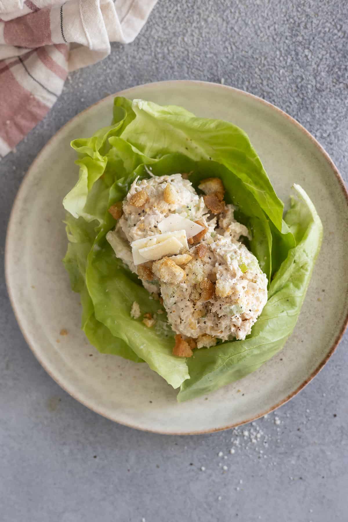 Overhead view of scoops of caesar chicken salad on a bed of lettuce.