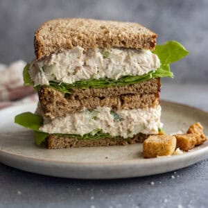 A sandwich cut in half stacked on each other showing the delicious caesar chicken salad.