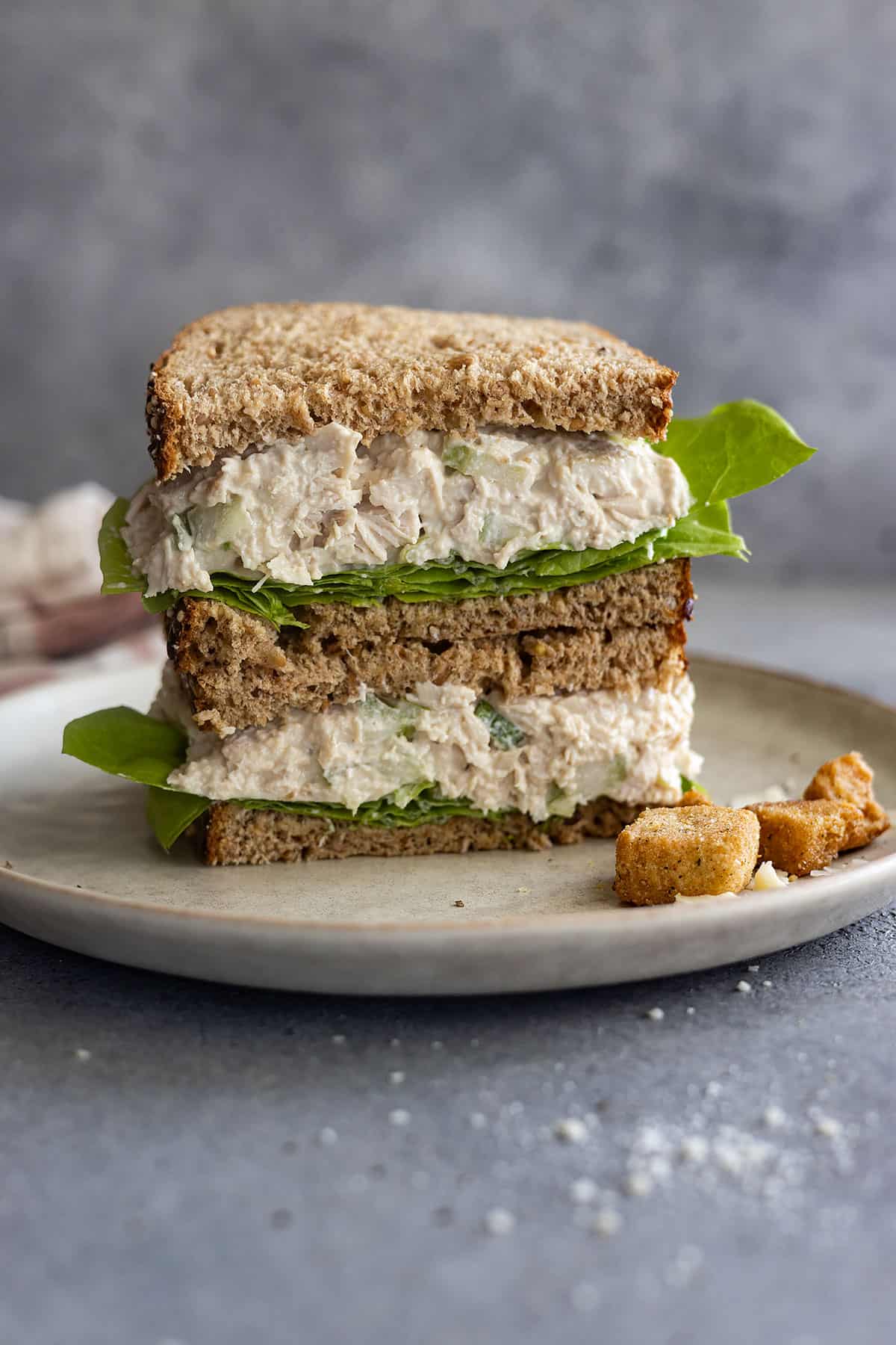 A sandwich cut in half stacked on each other showing the delicious caesar chicken salad.