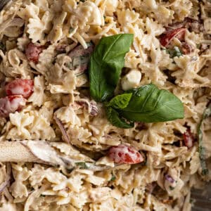 Overhead close up of marry me chicken pasta salad in a bowl with fresh basil leaves as garnish.