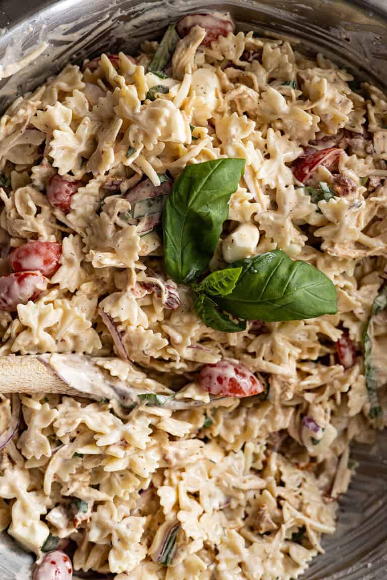 Overhead close up of marry me chicken pasta salad in a bowl with fresh basil leaves as garnish.