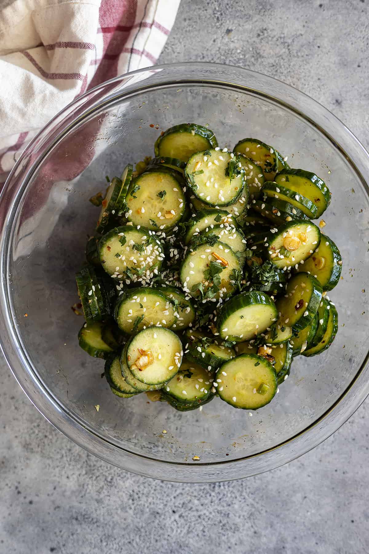 Asian cucumber salad in a clear bowl and salad garnished with sesame seeds.