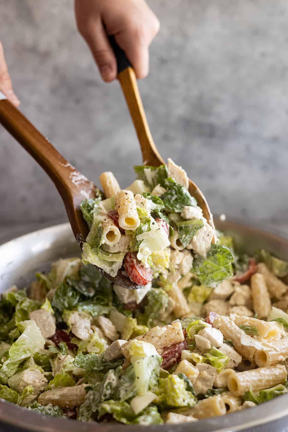 Two large spoons scooping up a portion of salad to serve.